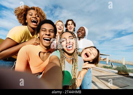 Glückliche und aufgeregte multikulturelle Freunde, die ein Selfie im Freien machen Stockfoto