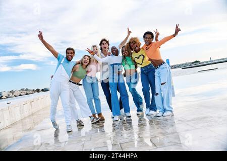 Multiethnische Freunde heben die Hände und lächeln draußen Stockfoto