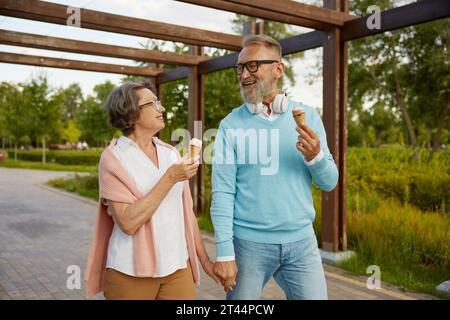 Fröhliches Seniorenpaar isst Eisbecher im Park und genießt entspannte Zeit Stockfoto