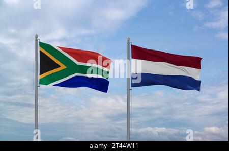 Die Flaggen der Niederlande und Südafrikas schwenken zusammen auf blauem bewölktem Himmel, zwei Länder-Beziehungskonzept Stockfoto