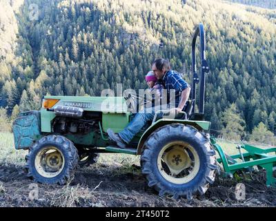 Der Landwirt fährt einen Traktor, da er das Rad während der Kartoffelernte an einem Herbsttag im Aostatal NW Italien hält. Oktober 2023 Stockfoto