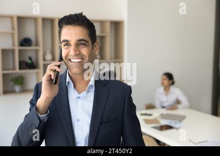 Fröhlicher, erfolgreicher, gutaussehender Geschäftsmann, der Mobiltelefonanrufe genießt Stockfoto