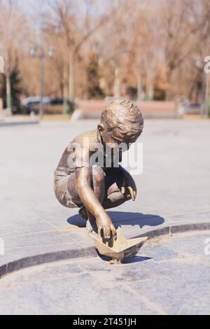 JEREWAN. ARMENIEN. 29. MÄRZ 2022: Bronzestatue eines glücklichen Jungen, der mit einem Papierboot im neuen Park spielt und dem 2800. Jahrestag der Fo gewidmet ist Stockfoto