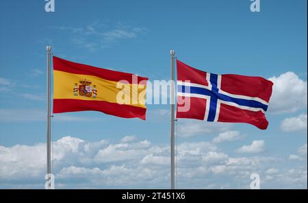 Norwegens und Spaniens Flaggen schwenken zusammen auf blauem bewölktem Himmel, zwei Länder-Beziehungskonzept Stockfoto