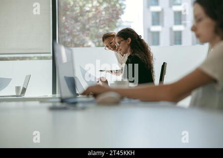 Zwei verschiedene Geschäftskollegen arbeiten mit Dokumenten, während sie im Büro mit einem Laptop arbeiten Stockfoto