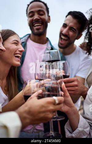 Vertikale Gruppen, multirassisch aufgeregt Freunde, die Rotwein trinken, um Sommerparty im Freien zu feiern. Stockfoto