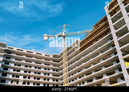 Ein großer Turmkran baut einen Eckhochhaus-Wohnkomplex Stockfoto