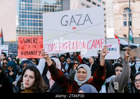 Toronto, Kanada - 28. Oktober 2023: Demonstranten in urbaner Umgebung. Die Frau hält ein Schild über Gaza und vergleicht es mit einem offenen Gefängnis und Konzentrationslager Stockfoto