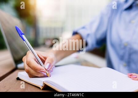 Großaufnahme Geschäftsfrau Hand hält Stift auf Notizbuch draußen Stockfoto