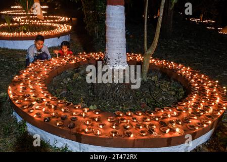 Mumbai, Indien. Oktober 2023. Ein Junge und ein Mädchen werden bei Sharad Purnima (Vollmond) in Mumbai mit Erdlampen angezündet. Sharad Purnima oder der Vollmond markiert das Ende der Monsunsaison und wird von den Hindus in ganz Südasien in den Monaten September bis Oktober auf vielfältige Weise gefeiert. Gläubige beobachten in der Vollmondnacht schnell. Lakshmi, Göttin des Reichtums, wird an diesem Tag verehrt, da es ihr Geburtstag sein soll, und zu ihr zu beten bringt Glück und Reichtum. Quelle: SOPA Images Limited/Alamy Live News Stockfoto