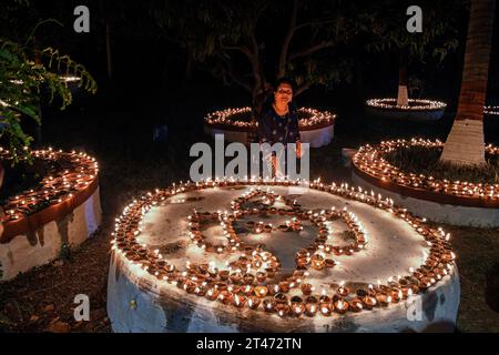 Mumbai, Indien. Oktober 2023. Eine Frau zündet eine irdene Lampe anlässlich der Sharad Purnima (Vollmond) in Mumbai an. Sharad Purnima oder der Vollmond markiert das Ende der Monsunsaison und wird von den Hindus in ganz Südasien in den Monaten September bis Oktober auf vielfältige Weise gefeiert. Gläubige beobachten in der Vollmondnacht schnell. Lakshmi, Göttin des Reichtums, wird an diesem Tag verehrt, da es ihr Geburtstag sein soll, und zu ihr zu beten bringt Glück und Reichtum. Quelle: SOPA Images Limited/Alamy Live News Stockfoto