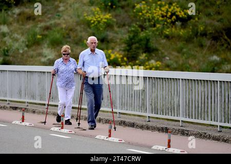 Ein älteres Paar ist Nordic Walking entlang einer Provinzstraße Stockfoto