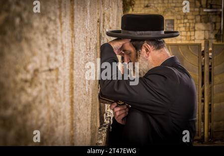 Der ultra-orthodoxe jüdische Mann (Haredi) betet mit Tora in der Hand an der Westmauer (Klagelmauer), dem Judentum-Schrein, in der Jerusalemer Altstadt in Israel. Stockfoto