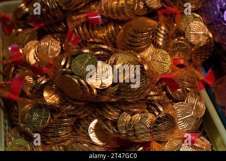 In Gold und Silberfolie gewickelte traditionelle Schokoladenmünzen in kleine Netztüten für den jüdischen Feiertag von Hanukka. Stockfoto