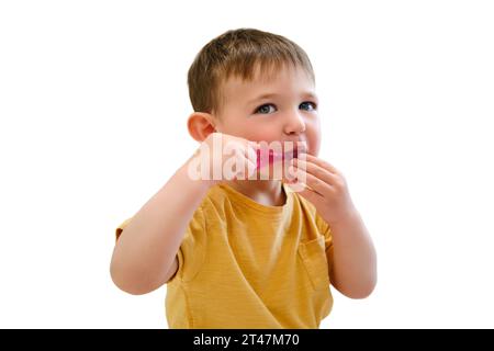 Mit einer Zahnbürste in der Hand sitzt das Baby zufrieden in ihrer Krippe und reinigt ihr perlweißes weiß, isoliert auf weißem Hintergrund. Kind im Alter von etwa zwei Jahren ( Stockfoto