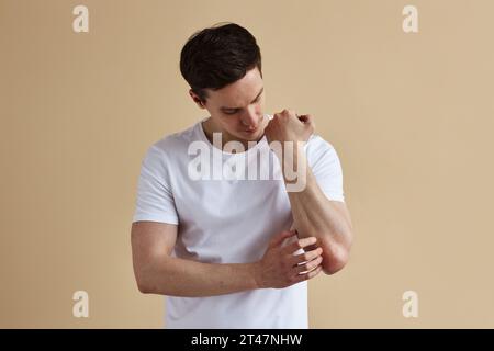 Minimales Porträt eines jungen Mannes, der bei Psoriasis an der Haut kratzt, Kopierraum Stockfoto