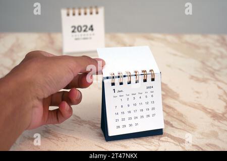 Die Hand eines Mannes dreht ein Kalenderblatt um. Januar des Jahres wechseln von 2023 auf 2024. Stockfoto