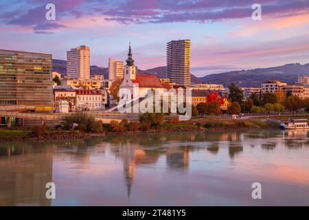 Linz, Österreich. Stadtbild des Flusses Linz, Österreich bei schönem Sonnenaufgang im Herbst mit einer Reflexion der Stadt in der Donau. Stockfoto