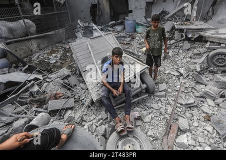 Al Bureij, Palästinensische Gebiete. Oktober 2023. Palästinensische Kinder sitzen nach israelischen Luftangriffen in den Trümmern zerstörter Gebäude um die Al-Bilal Moschee im Lager Al-Bureij. Quelle: Mohammed Talatene/dpa/Alamy Live News Stockfoto