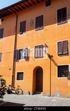 Hell gestrichenes Haus in Orange. Atemberaubender farbenfroher Hintergrund. Pisa, Italien Stockfoto