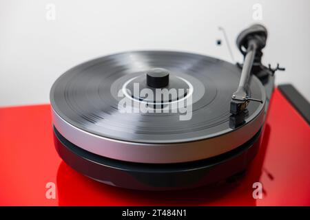 Nahaufnahme des hifi-Audio-Recorder-Players mit schwarzer Vinylscheibe, die elegant auf einem roten, hochwertigen hifi-Standfuß positioniert ist und fesselnde Melodien abspielt. Stockfoto