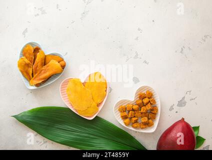 Getrocknete Mangoblätter und -Kugeln in herzförmigen Platten auf Leuchtplatte. Ansicht von oben. Stockfoto