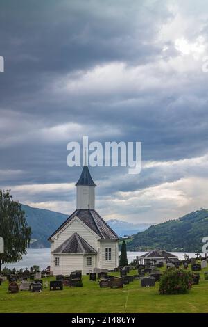 Loen, Norwegen, 26. Juni 2023: Die Loen-Kirche, eine Pfarrkirche der norwegischen Kirche, hier von hinten auf dem Friedhof, an einem bewölkten Abend dargestellt Stockfoto