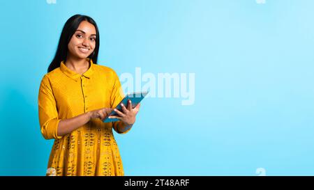 Die Hindu-Dame posiert mit einer Tafel, die gelb gekleidet ist, im Studio Stockfoto