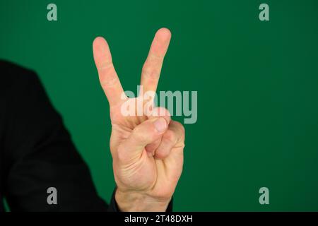 Die Hand eines jungen Mannes mit einem schwarzen Hemdärmel isoliert auf Grün. Hochwertige Fotos Stockfoto