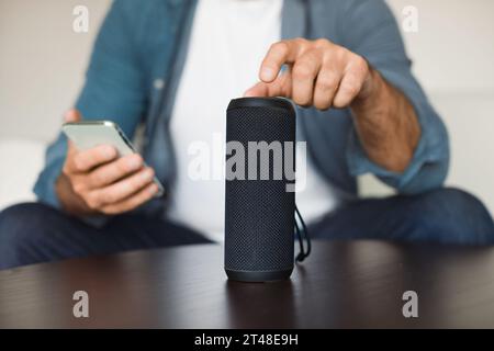 Nicht Wiedererkennbarer Mann, Der Musik Über Smart Speaker Und Smartphone In Innenräumen Hört Stockfoto