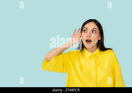 Neugierige junge Frau, die abhört, Hand neben Ohr hält Stockfoto