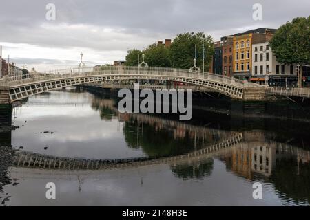 Die ha'Penny Bridge ist eine Fußgängerbrücke über den Fluss Liffey in Dublin, Irland, die für ihr schönes gusseisernes Design und ihren ikonischen Status bekannt ist. Stockfoto