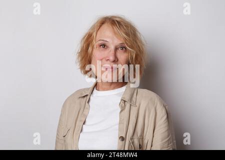 Positive, nette Frau mit blondem bob-Haar, die in die Kamera auf weißem Hintergrund blickt Stockfoto