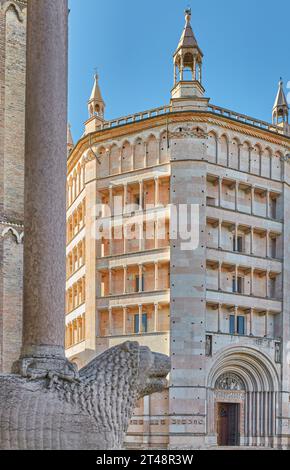 Parma, Italien, das achteckige Baptisterium aus rosafarbenem Marmor im romanischen lombardischen Stil mit einem Marmorlöwen am Eingang der Kathedrale im Vordergrund Stockfoto