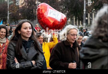 Amsterdam, Niederlande. Oktober 2023. Da es keine Nationalflaggen oder andere, auf das Land ausgerichtete Utensilien gibt, laufen Tausende von Menschen schweigend durch das Zentrum von Amsterdam, um für den Frieden zu demonstrieren. Angesichts des andauernden Krieges zwischen der Ukraine und Russland sowie Israel und Palästina fordert der marsch ein Ende aller Feindseligkeiten. Hör auf, auf einen großen Ballon in Form eines roten Herzens zu schießen. Frieden, Vredesmars, Demonstratie, Manifestatie, Credit: Imago/Alamy Live News Stockfoto