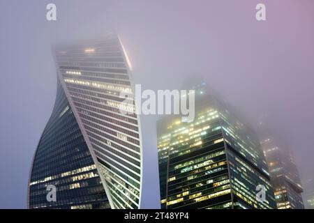 Die Spitzen moderner Firmengebäude vor dem nebeligen Himmel bei Nacht. Hochhäuser und Wolkenkratzer Moscow International Business Center. Stockfoto