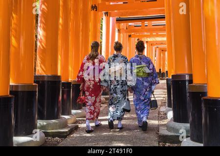 Kyoto, Japan - 17. April 2023: Drei europäische Frauen in Kimono, die durch den Torii-Pfad am Fushimi Inari-Taisha-Schrein laufen, dem Hauptschrein des Th Stockfoto