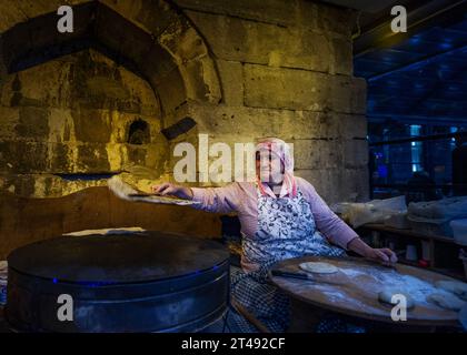 20. September 2022 - Istanbul Türkei-erfahrene alte Frau backt Brot auf einem Metallgrill in einem Istanbul Restaurant, das den Gästen heiß serviert wird Stockfoto