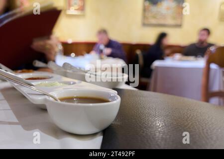 Verschiedene Saucen in weißen Behältern auf weißer Tischdecke. Stockfoto