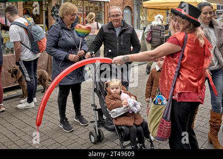 Weibliche Straßenunterhalterin formt einen Ballon für ein Kind. England Großbritannien Stockfoto