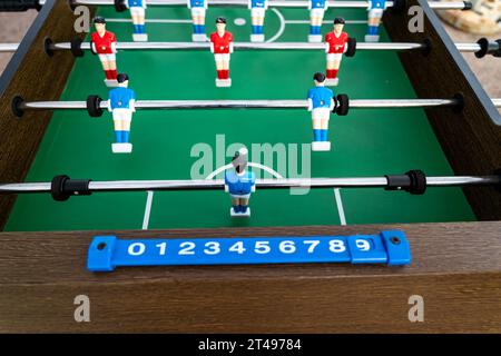 Tischfußball. Nahaufnahme von Figuren von Plastikspielern in einem Fußballspiel. Rote und blaue Spieler treten den Ball. Stockfoto