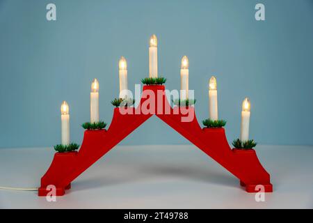 Traditioneller Weihnachtskerzenhalter mit sieben Kerzen auf blauem Winterhintergrund. Weihnachtskerzenbrücke mit sieben Kerzenlichtern. Dekoration für t Stockfoto