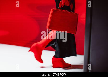 Modische Details von schwarzem langem Rock, roten Handschuhen, Lederhandtasche und High Heels. Modemodell auf dem Laufsteg Stockfoto