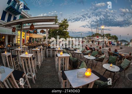 SKIATHOS STADT, SPORADEN INSELN, GRIECHENLAND - 22. AUGUST 2023: Schöne Bar im alten und touristischen Hafen, bereit für Gäste bei Sonnenuntergang. Stockfoto