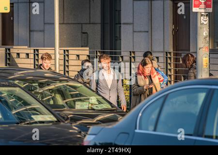 Junge Leute, beleuchtet von der Sonne, gehen zur morgendlichen Rushhour in Dublin zur Arbeit. Irland Stockfoto