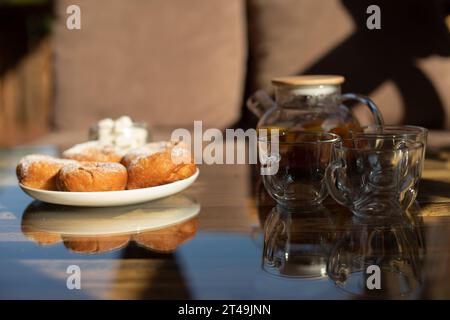 Tee mit Donuts auf dem Tisch. Köstliches Essen im Sommer. Details zum Tisch im Restaurant. Donuts in Platte. Stockfoto