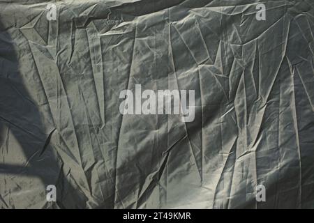 Zerknitterter Stoff in schwarzer Farbe. Oberfläche der Markise. Zerknitterte Textur. Falzlinien. Stockfoto