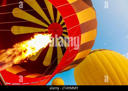 Heißluftballons fliegen bei Sonnenaufgang in der Türkei. Ihre farbenfrohen Baldachin fangen die letzten Lichtstrahlen ein und beleuchten die surreale Landschaft unterhalb des Stockfoto