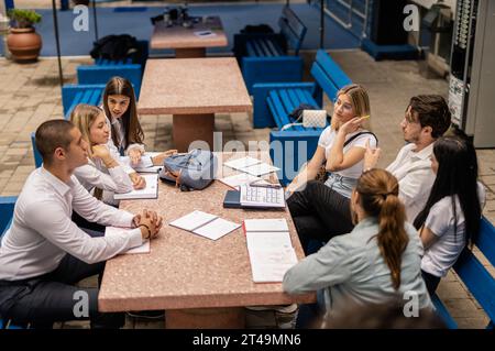 Eine große Gruppe von Studierenden versammelte sich am Tisch im Universitätshof, teilte Wissen und bereitete die Prüfung gemeinsam vor Stockfoto