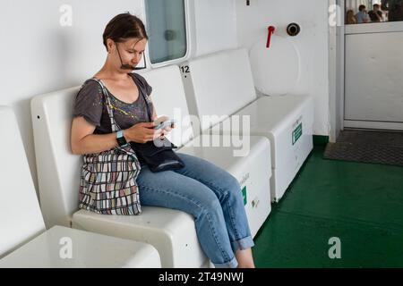 Eine Frau schaut über ihre Schatten, um ihr Handy auf einer Ostseekreuzfahrt zwischen Helsinki in Finnland, Åland und Stockholm in Schweden zu überprüfen. Stockfoto